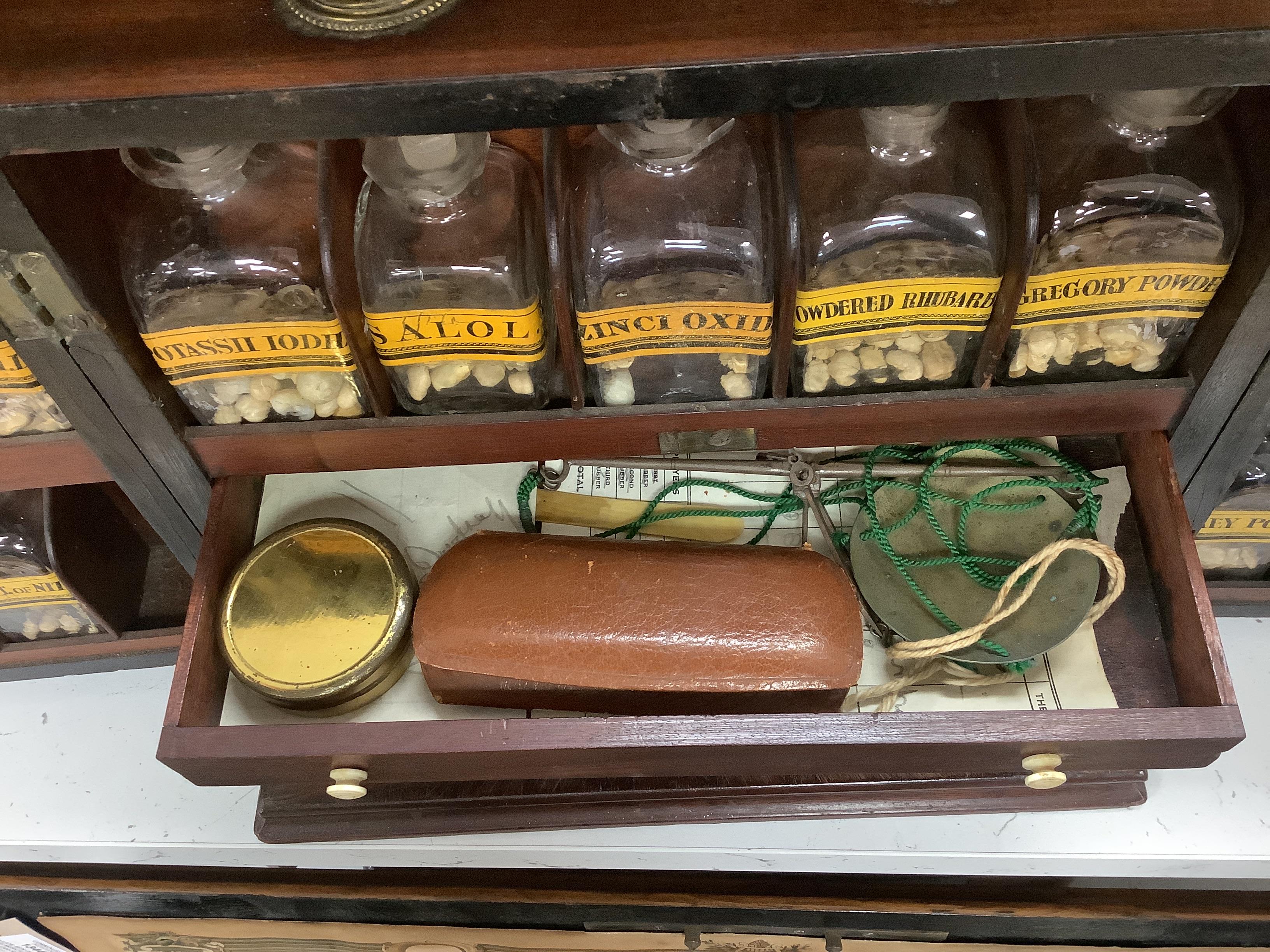 A Georgian mahogany domestic medicine chest, with bone drawer knobs and escutcheons, containing a number of glass square section drug bottles, fitted drawers containing scales, a pestle and mortar, etc., 29cm wide, 25cm